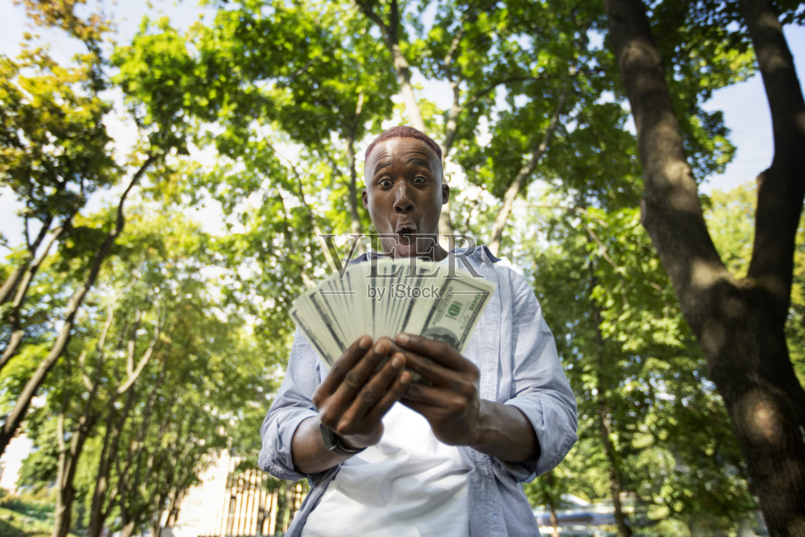 震惊的黑人与巨大的球迷的钱在城市公园照片摄影图片