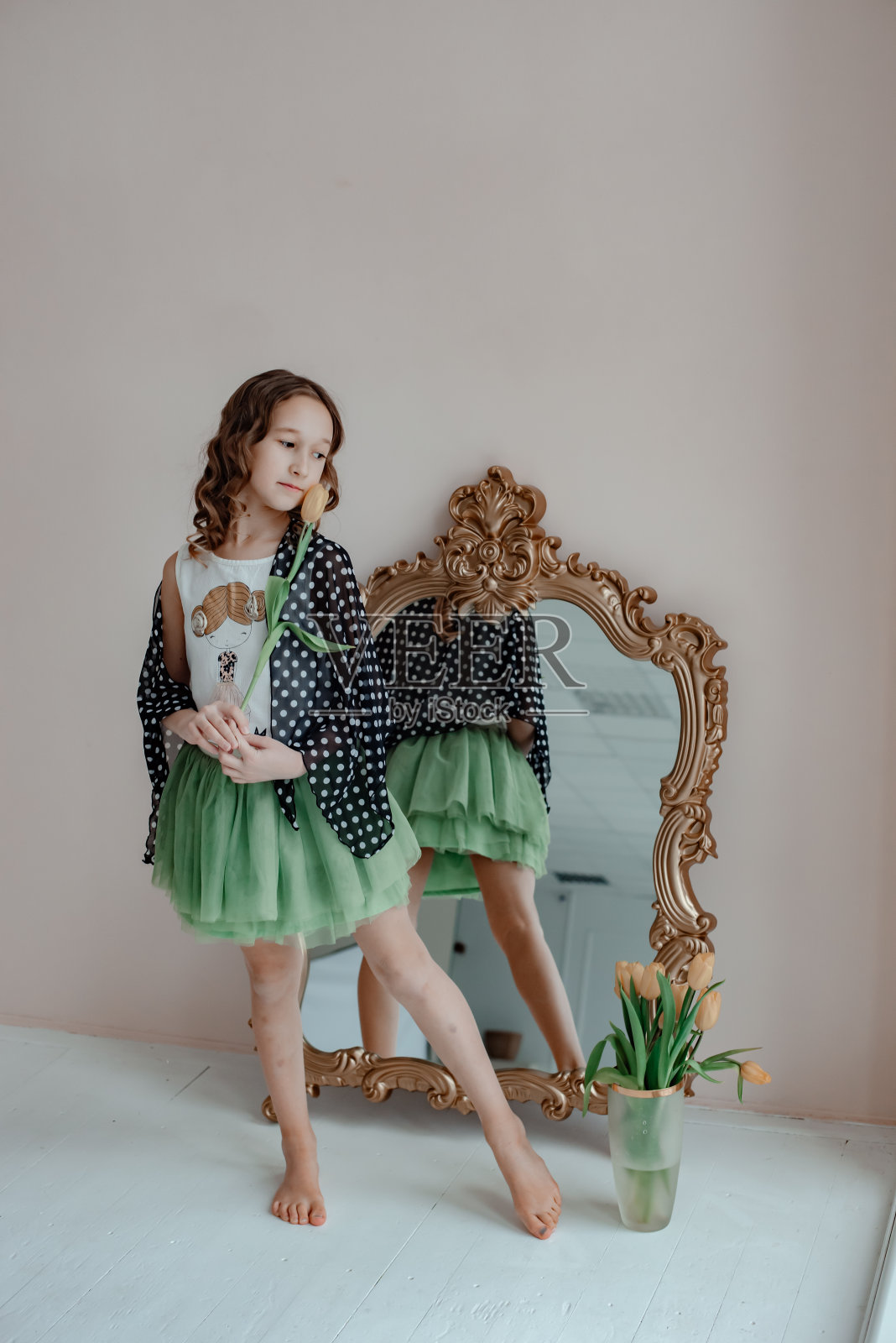 女孩在镜子前摆姿势。束郁金香。照片摄影图片