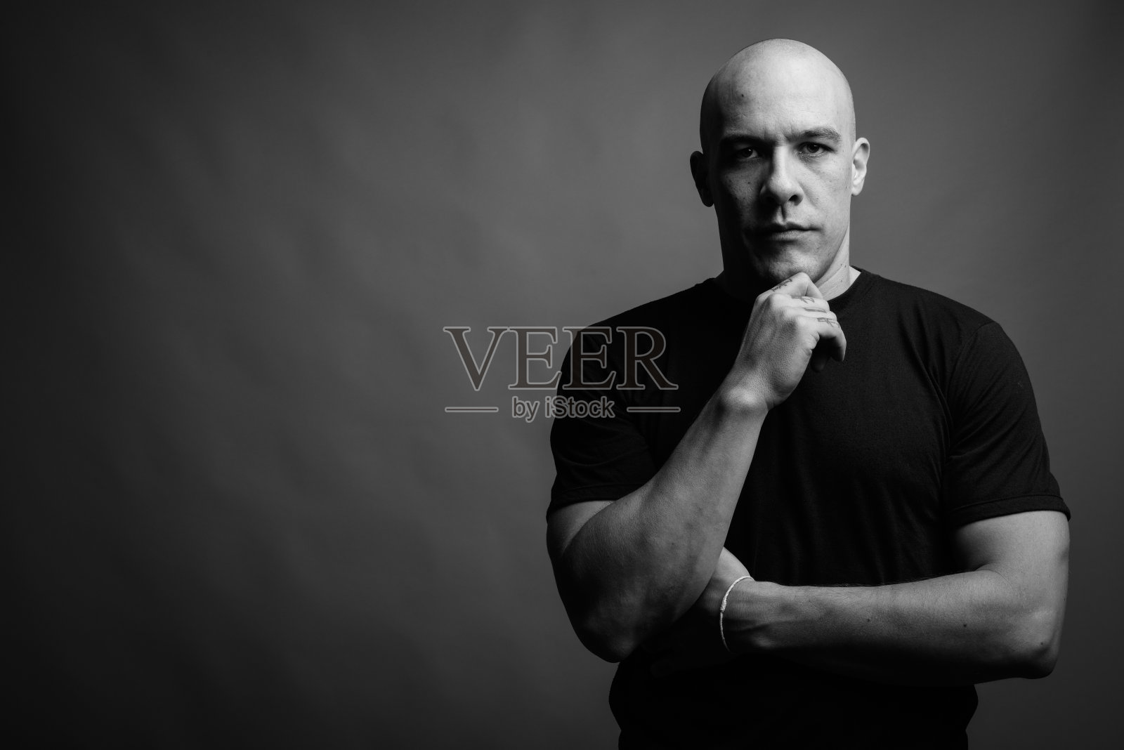 英俊的秃顶男子与手在灰色背景的黑色和白色照片摄影图片