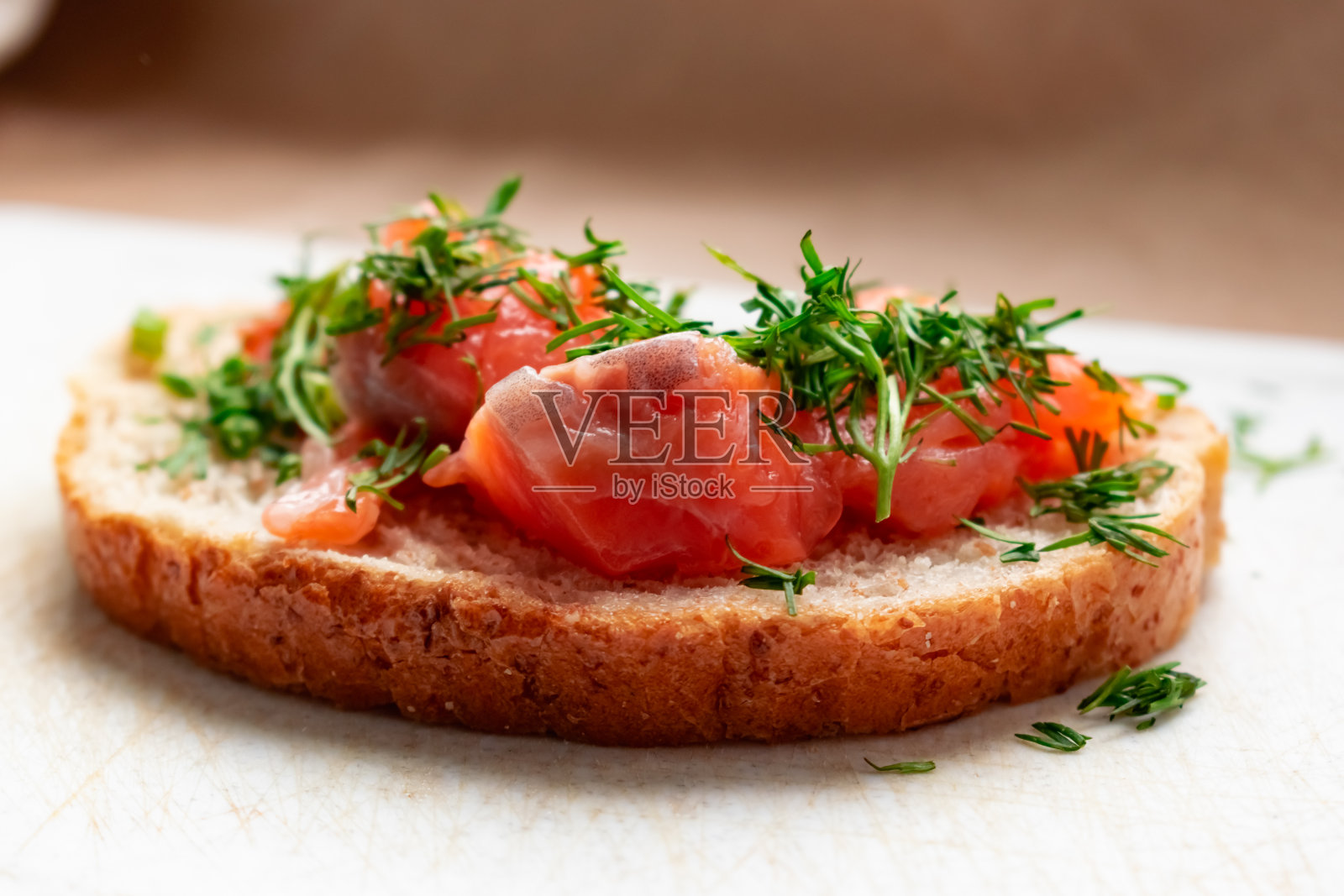 开胃的红鱼三明治，腌鲑鱼，在一块面包与麸皮，装饰切碎的莳萝照片摄影图片