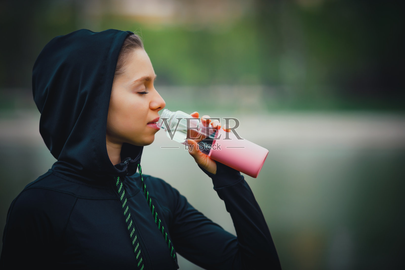 迷人的女孩用她的手机，无线耳机在公园里跑步照片摄影图片