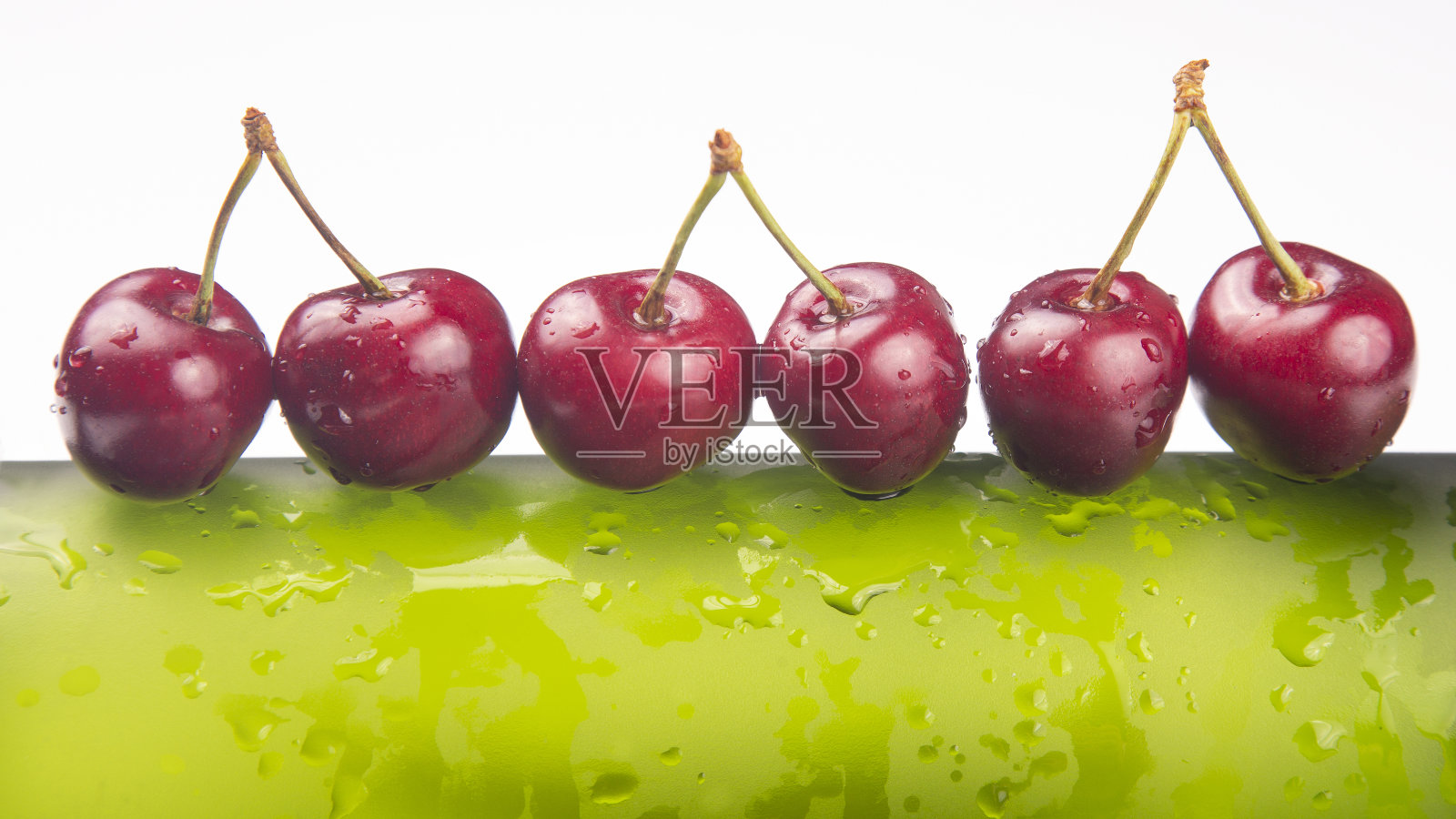 绿色瓶子上有新鲜的樱桃浆果和水滴。健康的早餐。植物的果实。水果甜点照片摄影图片