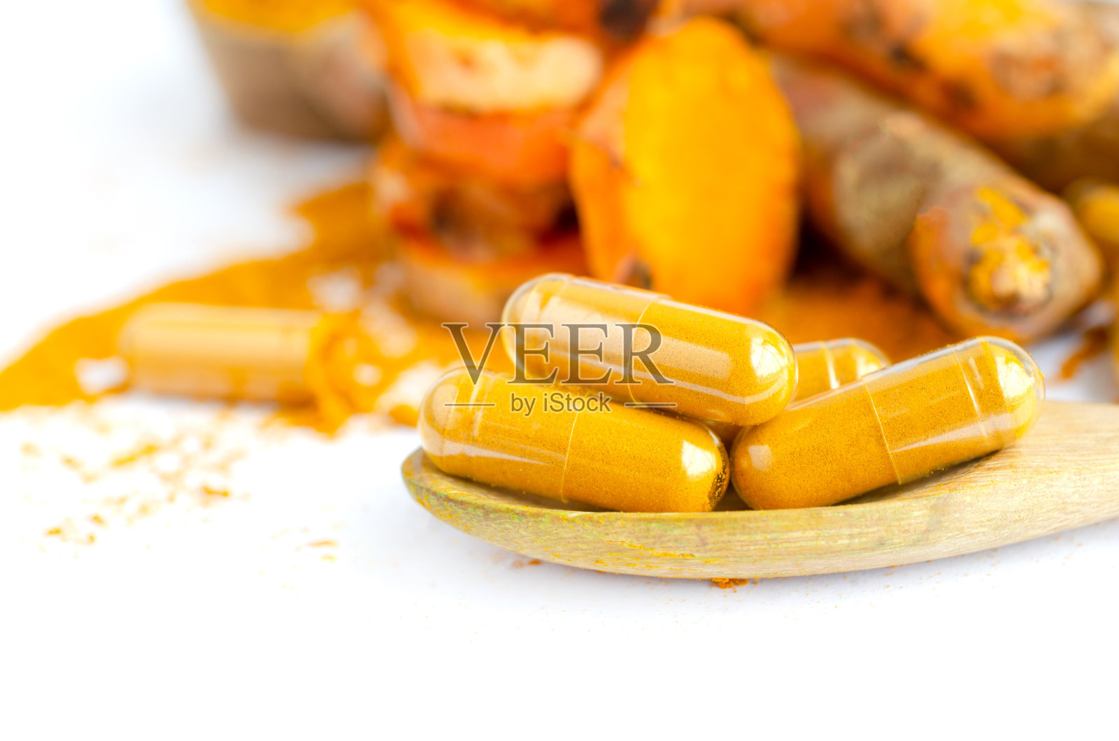 封闭的干燥有机姜黄粉胶囊在木勺上白色的背景照片摄影图片
