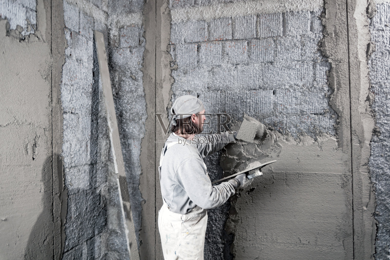 真正的建筑工人在新房子的墙壁上工作。照片摄影图片