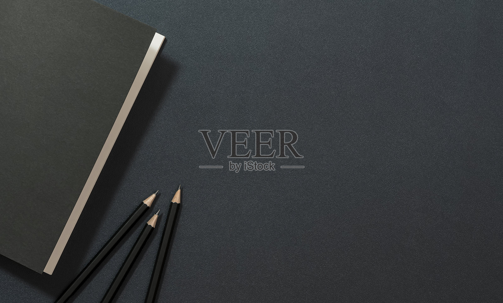 模型黑色封面书和铅笔在黑色皮革背景。照片摄影图片