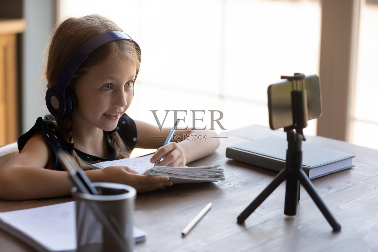 快乐的小女生戴着耳机在家学习照片摄影图片