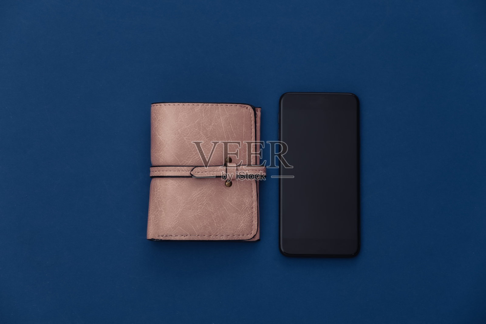 经典蓝色背景下的智能手机和钱包。颜色2020。前视图。照片摄影图片