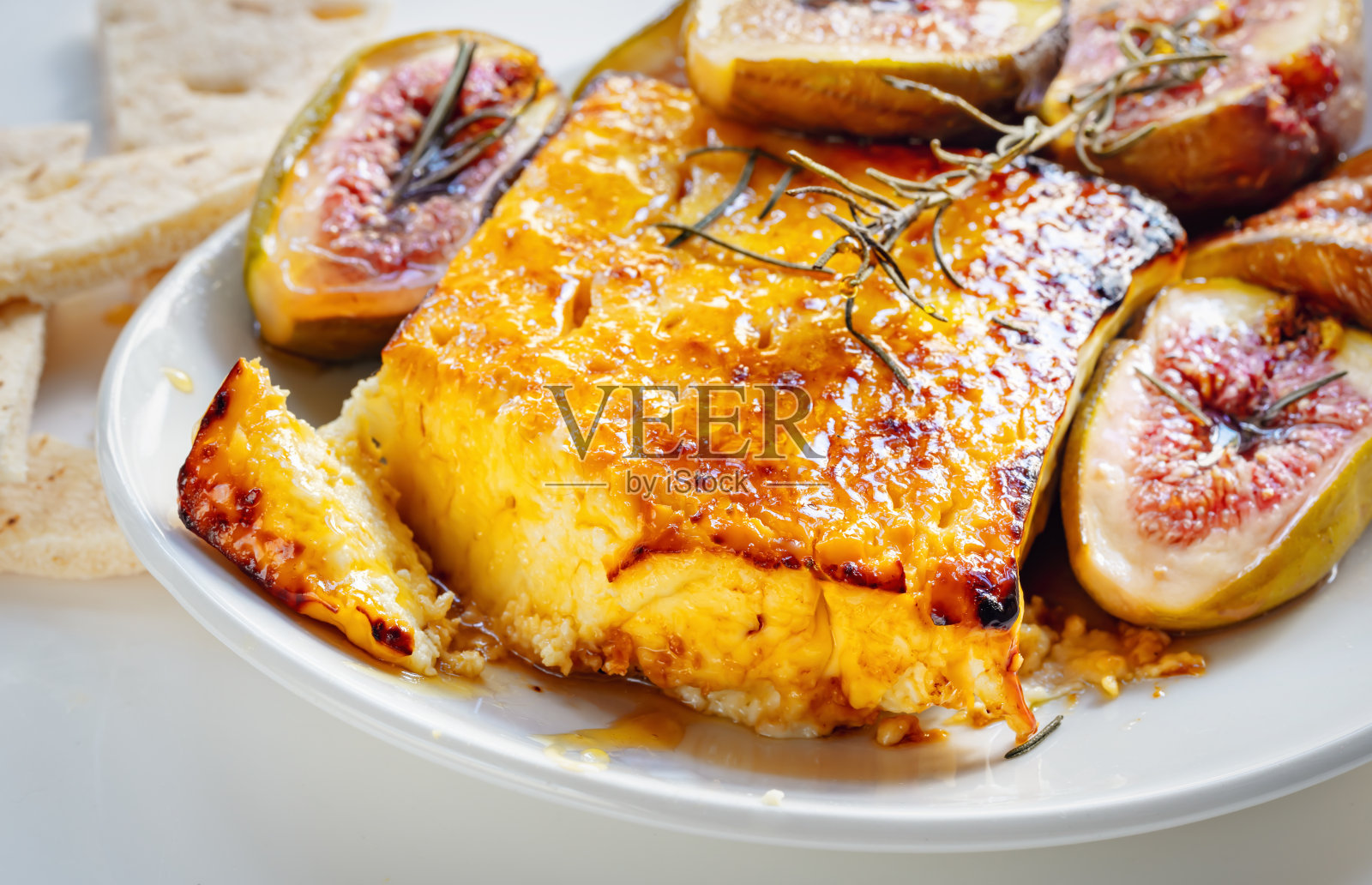 烤羊乳酪配蜂蜜和迷迭香，配烤无花果和皮塔饼。侧视图。照片摄影图片