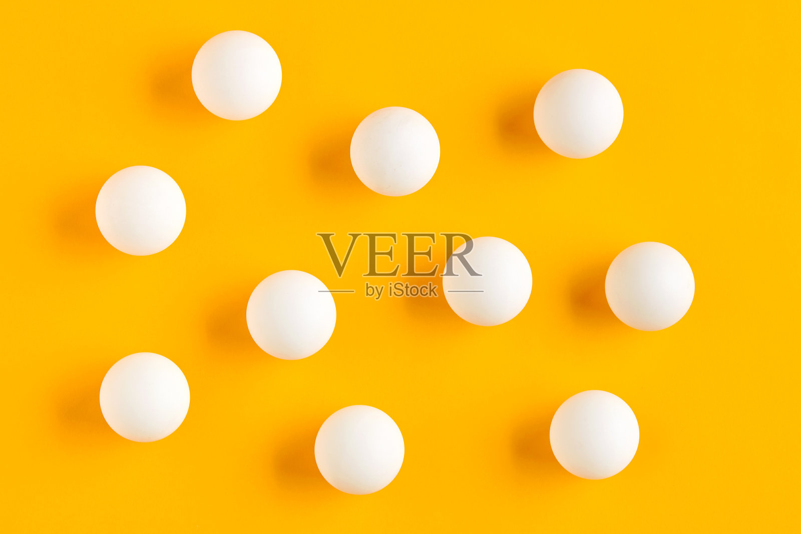 黄色背景上的白色乒乓球。照片摄影图片