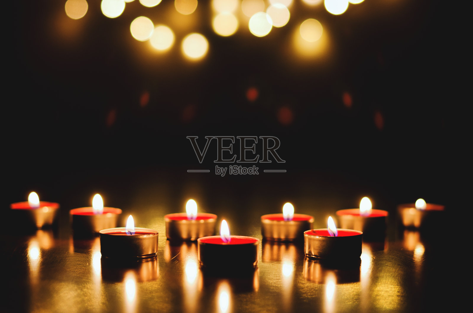 燃烧的蜡烛与节日的散景在黑色的背景。假日和浪漫的概念。祈祷和希望的概念照片摄影图片