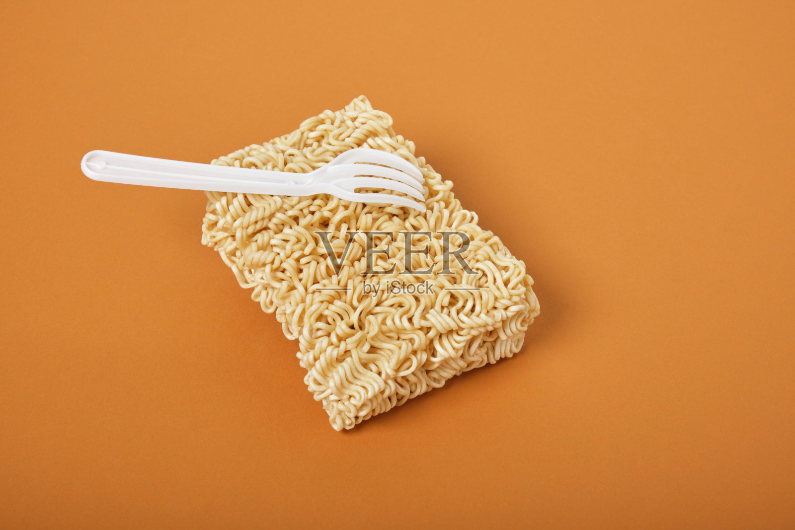 白色一次性塑料叉和干方便面块在棕色的背景上照片摄影图片