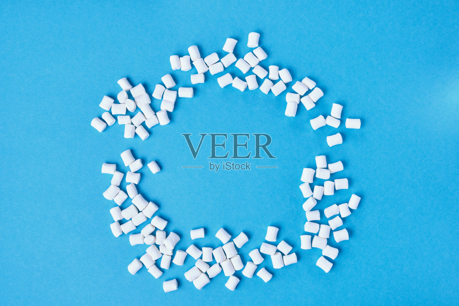 小的白色棉花糖分散在蓝色的背景空间复制，圆棉花糖俯视图模拟起来照片摄影图片