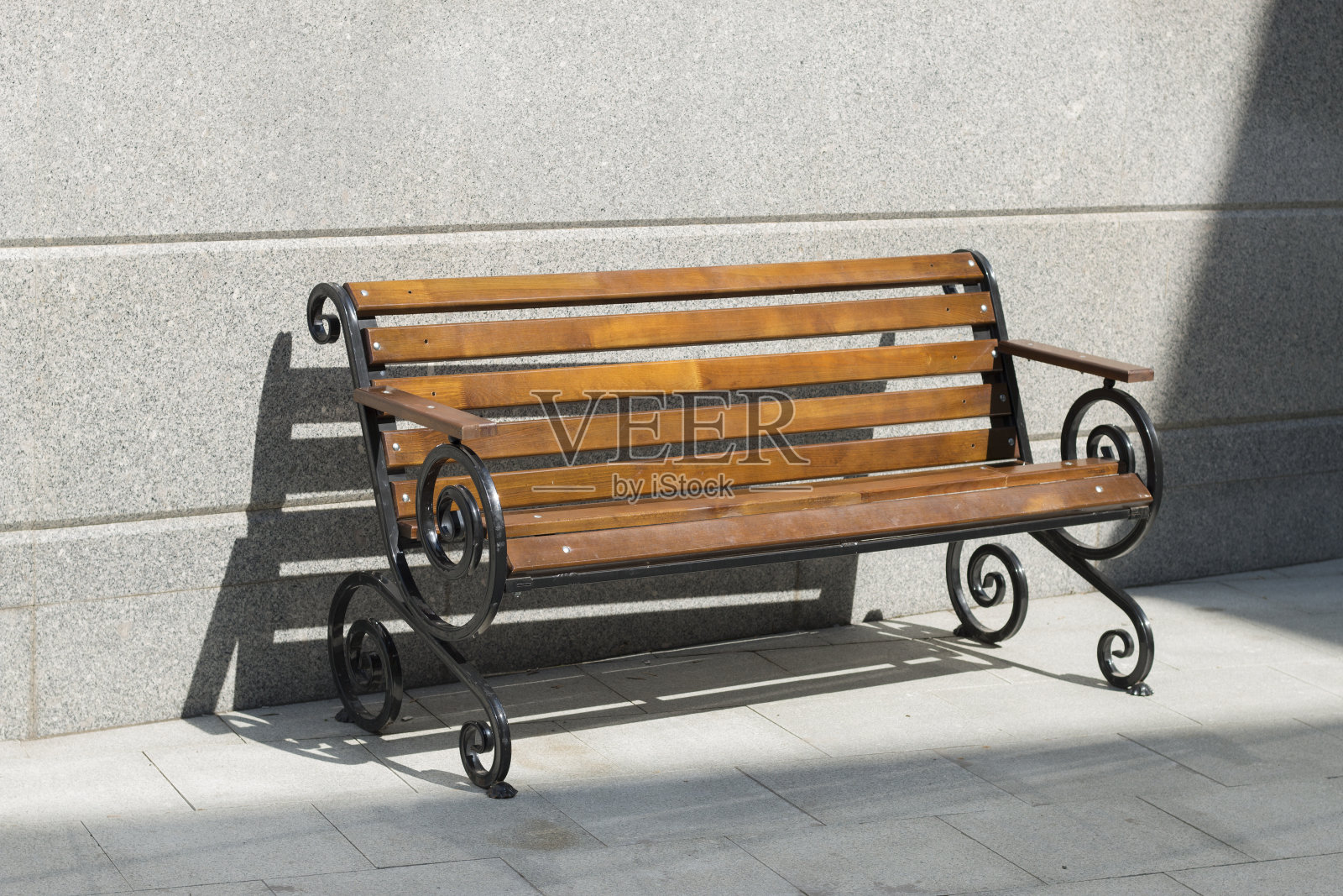 阳光明媚的日子里，混凝土中间空荡荡的木凳。照片摄影图片