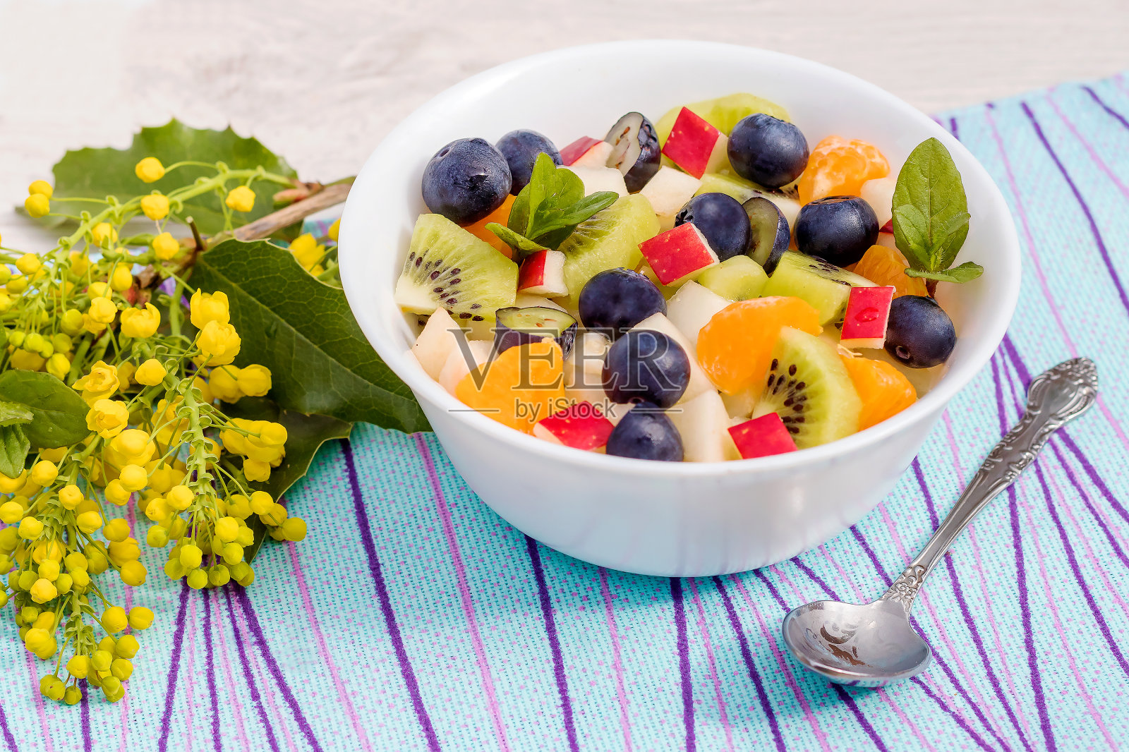 水果，新鲜的维生素，开胃的健康沙拉在一个白色的陶碗。照片摄影图片