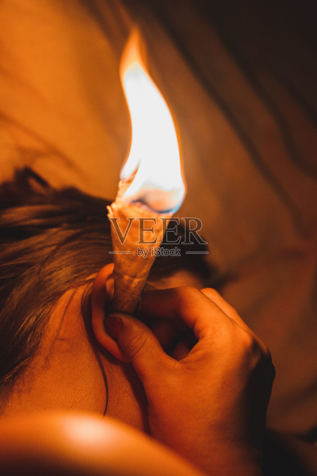 一位妇女接受蜡烛程序与自然疗法。照片摄影图片