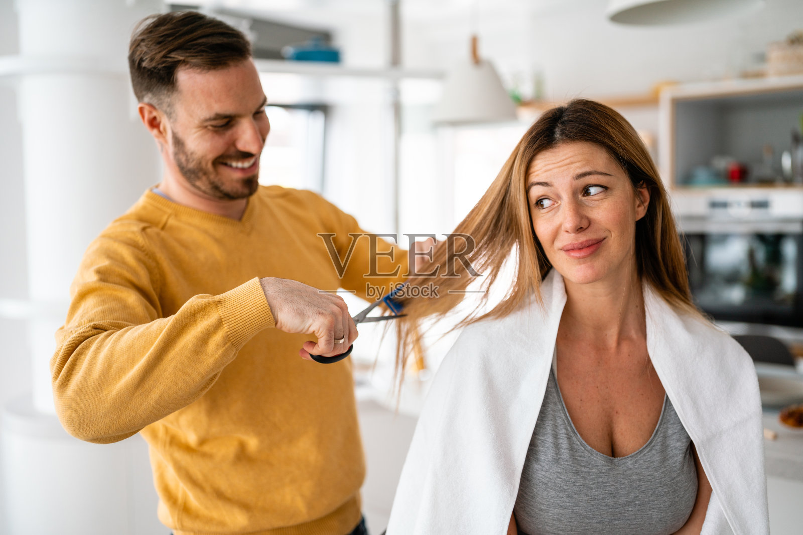 在隔离期间，男人在家里给女人理发。照片摄影图片