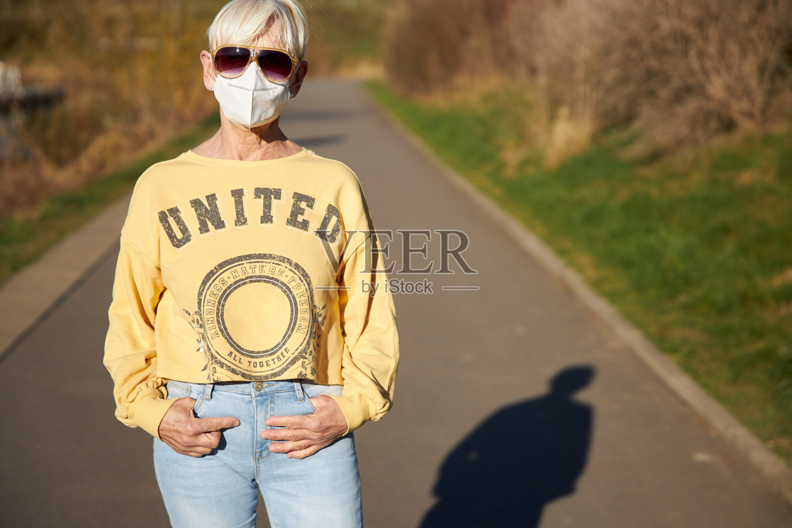 德国一名60岁的金发女子戴着黄色太阳镜和白色FFP 2面具照片摄影图片