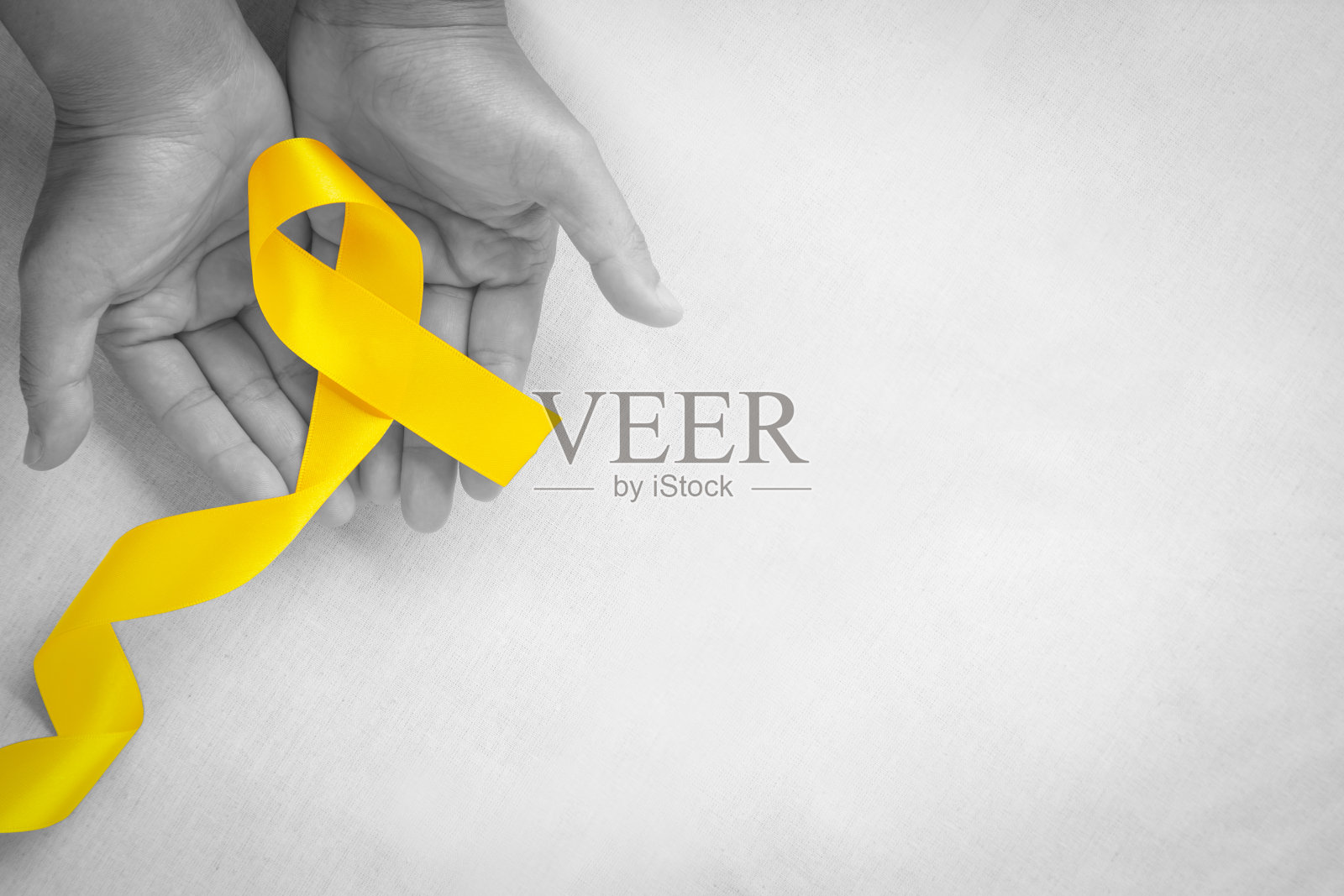 手握黄色丝带在白色背景，复制空间。骨癌，肉瘤意识，儿童癌症，胆管癌，胆囊癌，世界预防自杀日。健康的概念。照片摄影图片