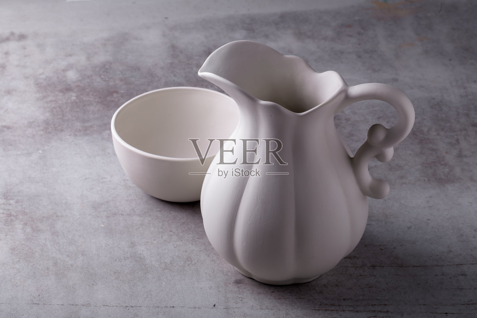 水泥板上的茶壶、奶油、杯子和碟子照片摄影图片