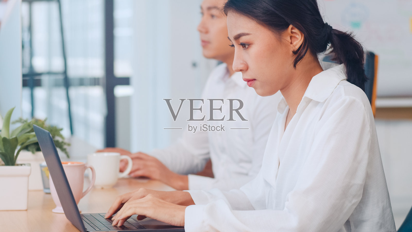 年轻的商业女性智能休闲装观看教程关于创意在笔记本电脑在现代办公室工作过程中。照片摄影图片