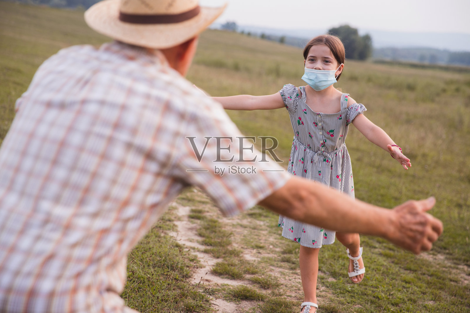 年轻的女孩戴着防护面具跑进爷爷的怀里照片摄影图片