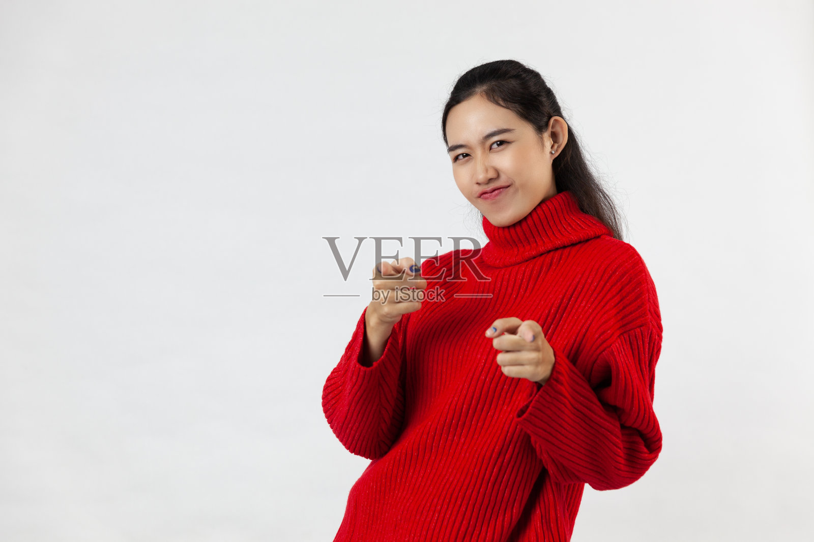 一名身穿红色毛衣的年轻亚洲女子指着站在白色背景上的摄像机照片摄影图片
