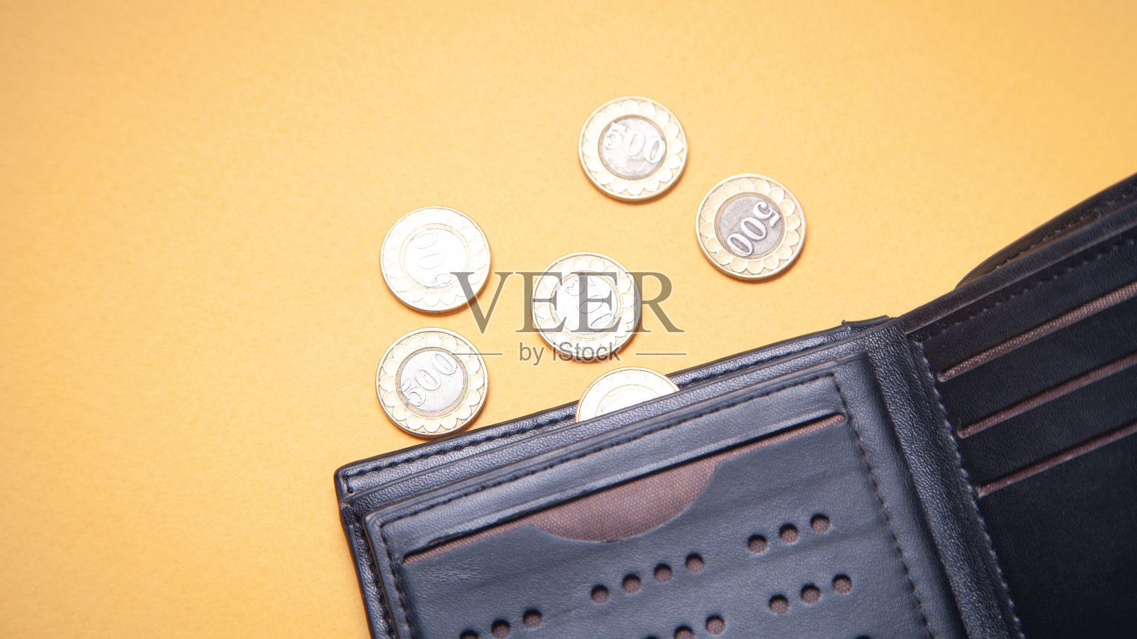 黄色背景上的钱包和硬币。照片摄影图片