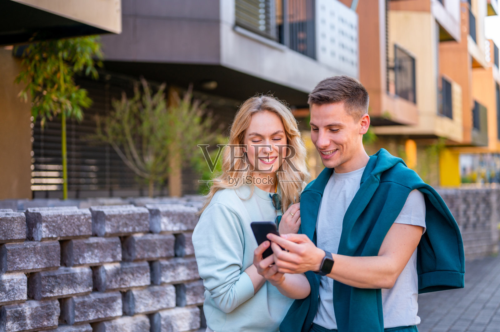 一对快乐的年轻夫妇在户外看智能手机照片摄影图片