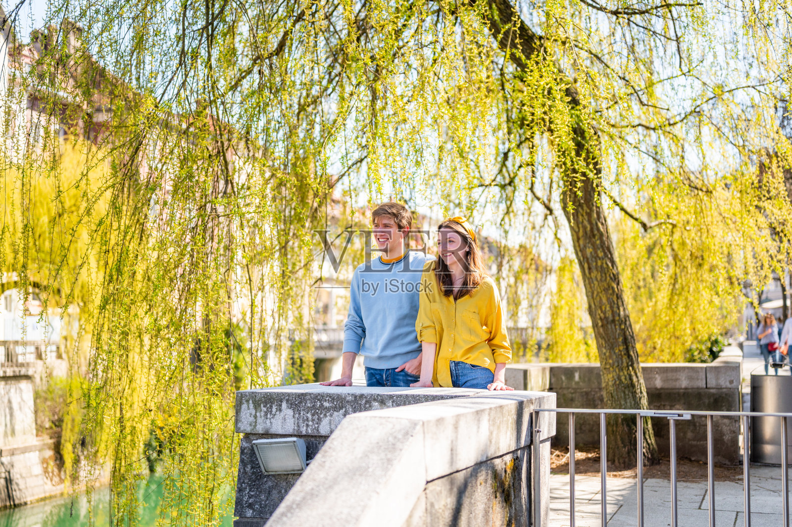 一对快乐的年轻夫妇站在城市的树下欣赏风景照片摄影图片