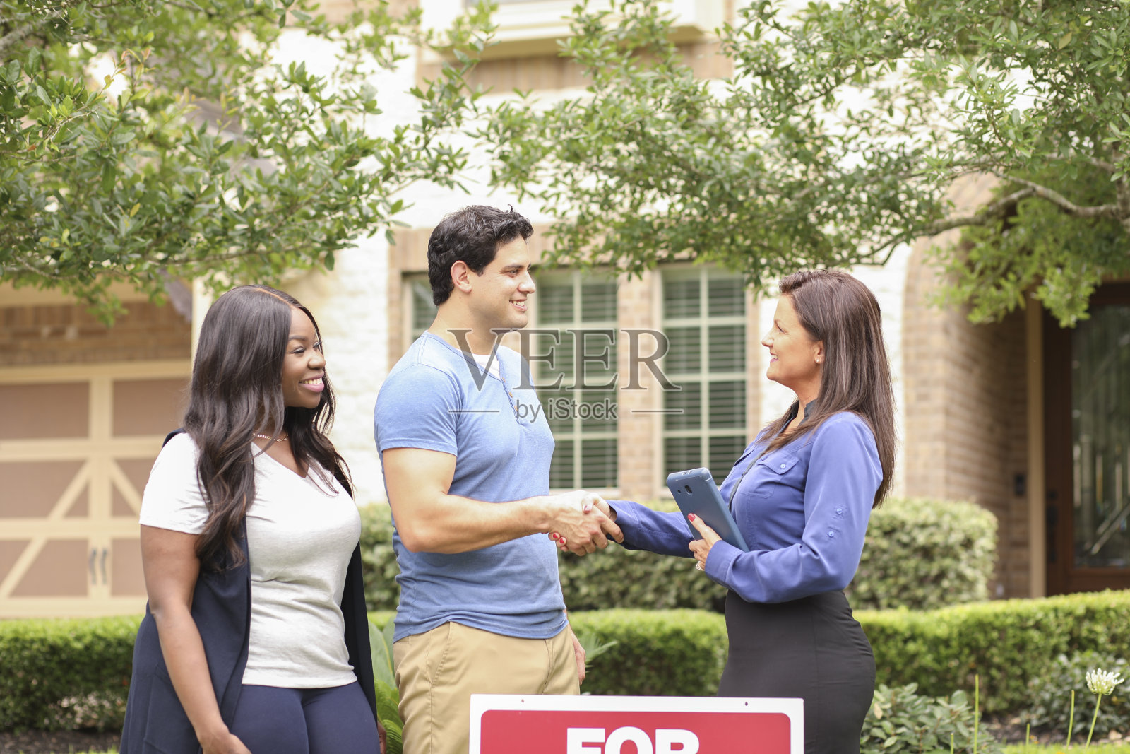 房地产经纪人和年轻夫妇买房。照片摄影图片