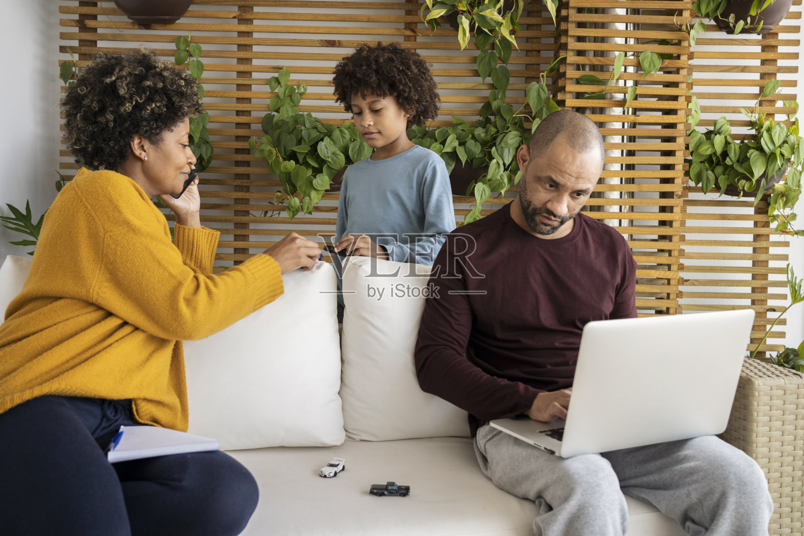 一对非洲裔美国商业夫妇和家庭在家里工作，他们的儿子打断和玩耍。照片摄影图片