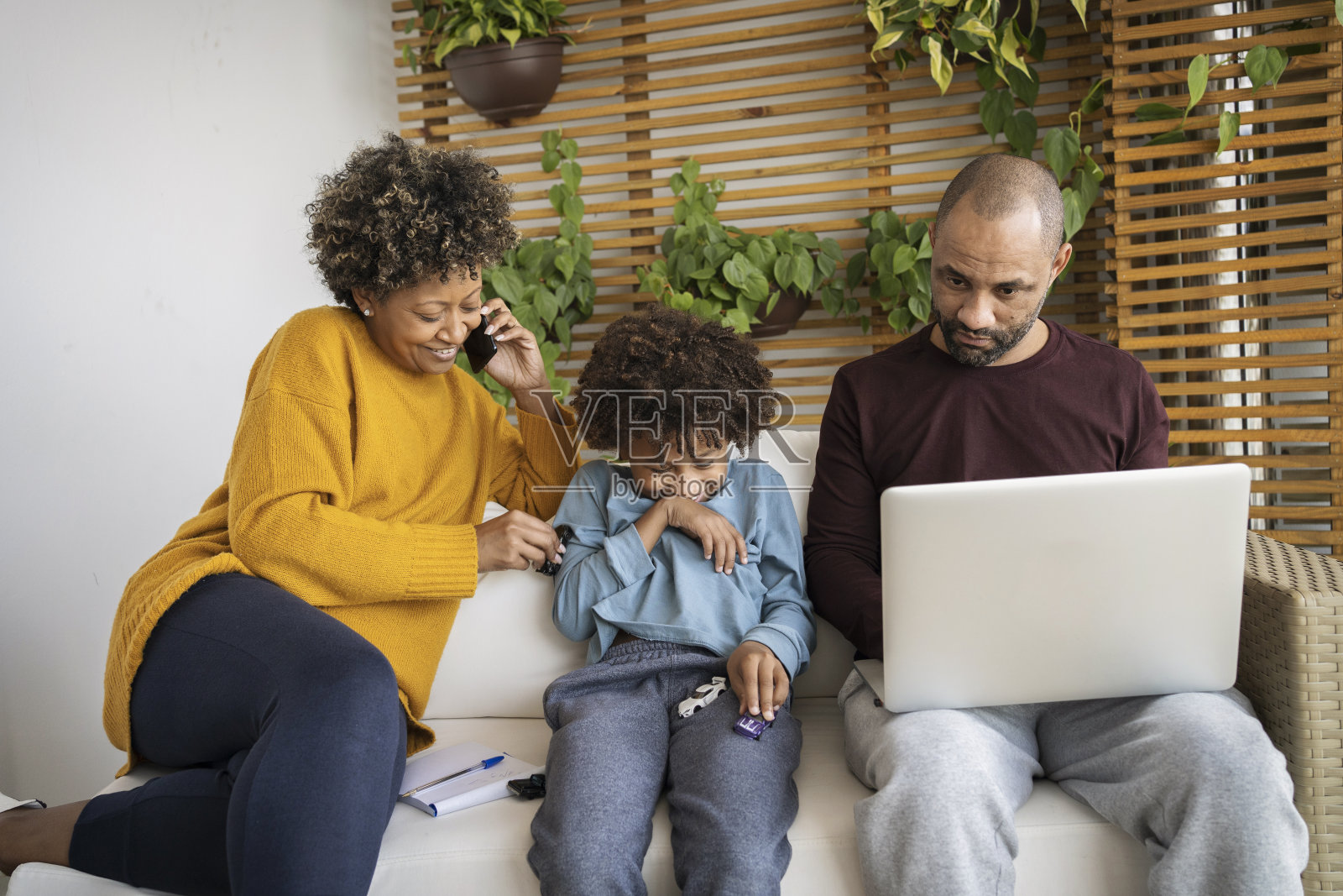 一对非洲裔美国商业夫妇和家庭在家里工作，他们的儿子打断和玩耍。照片摄影图片