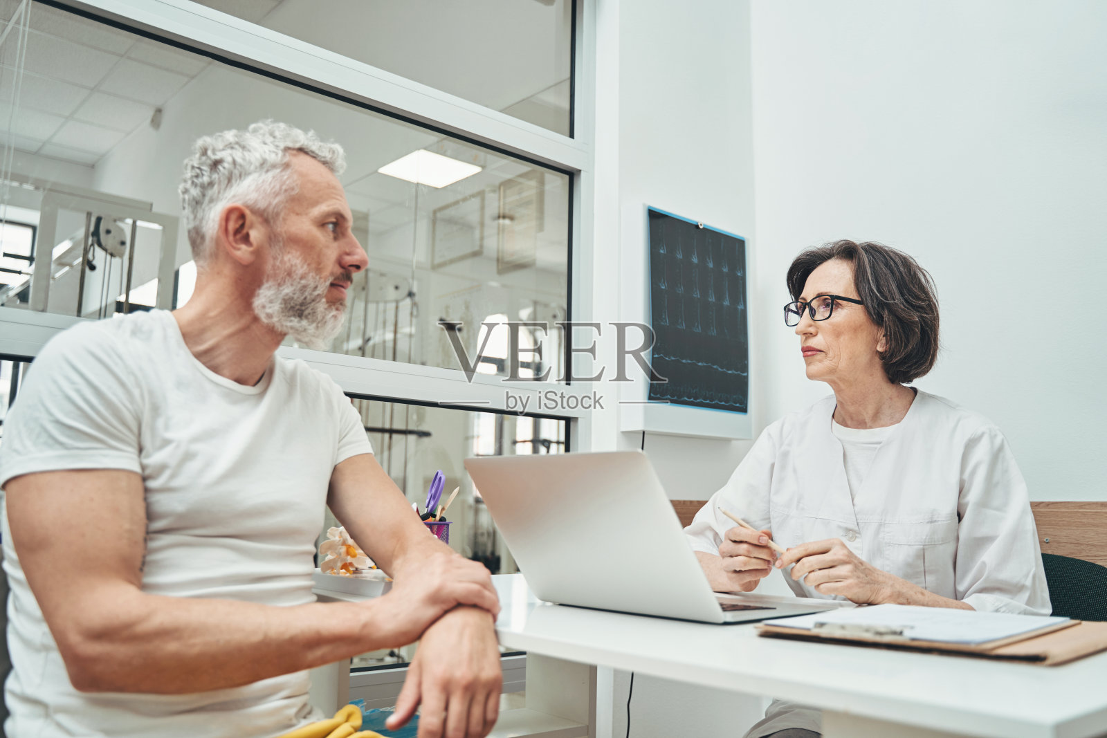 严肃冷静的脊椎专家在她的私人办公室里接待病人照片摄影图片