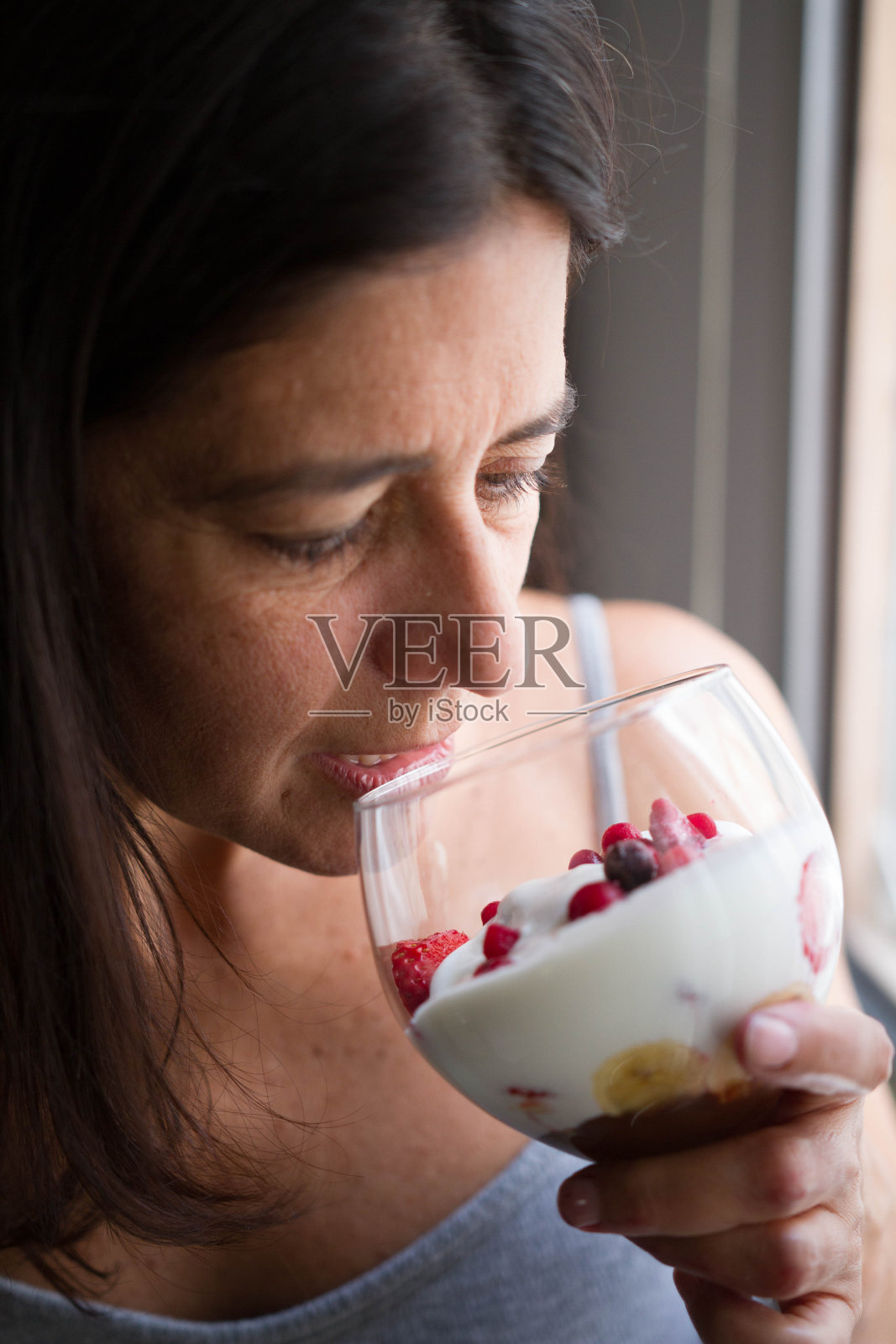 迷人的中年深色头发的西班牙女人与一杯冰激淋水果摆姿势照片摄影图片