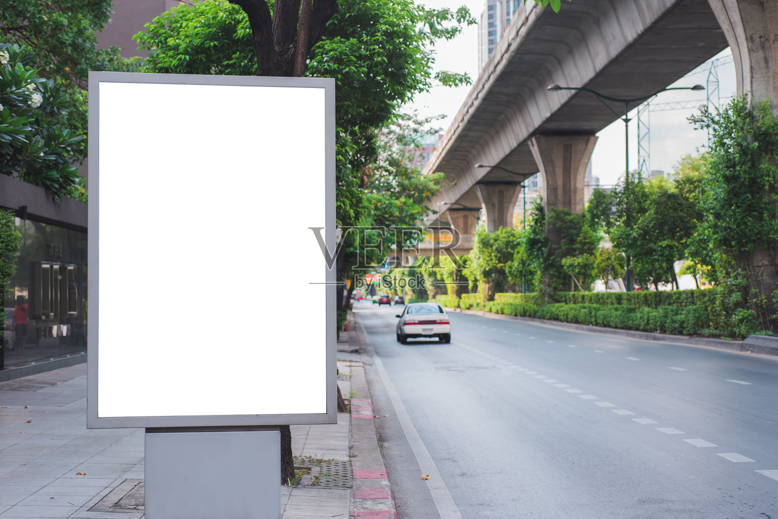 大空白广告牌白色LED屏幕垂直突出在城市边道路交通为展示广告文本模板推广新品牌在户外以绿树复古色调。照片摄影图片