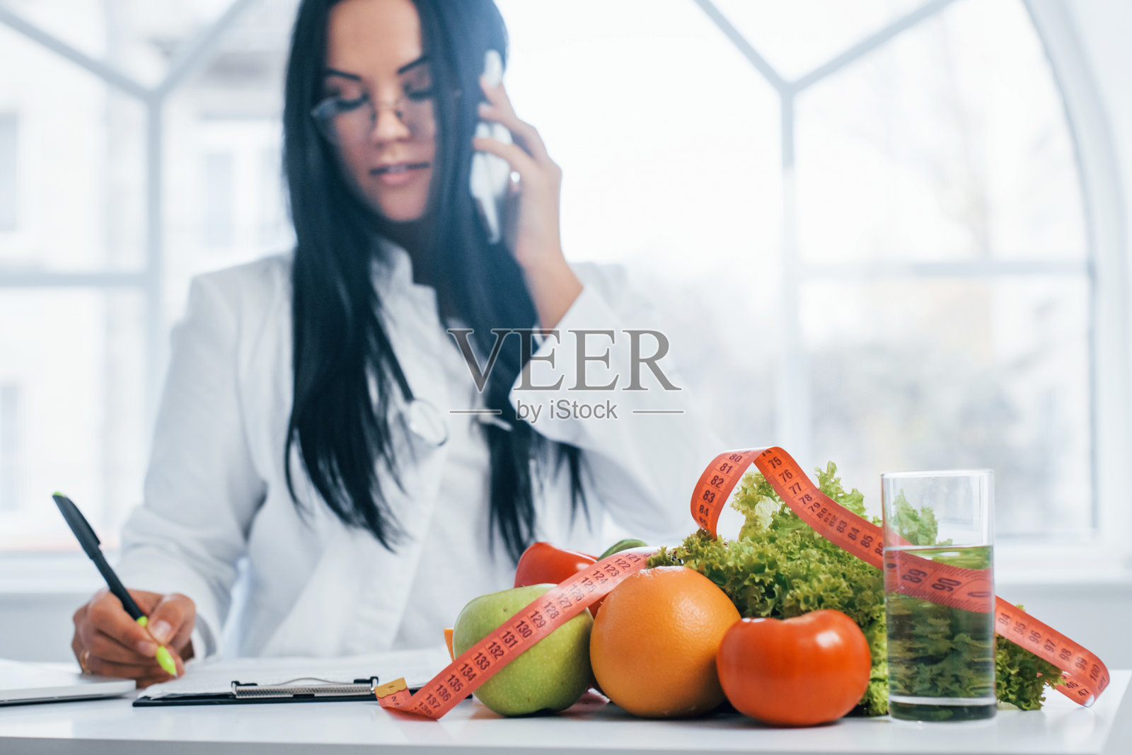 穿着白大褂坐在办公室室内的女性营养学家照片摄影图片