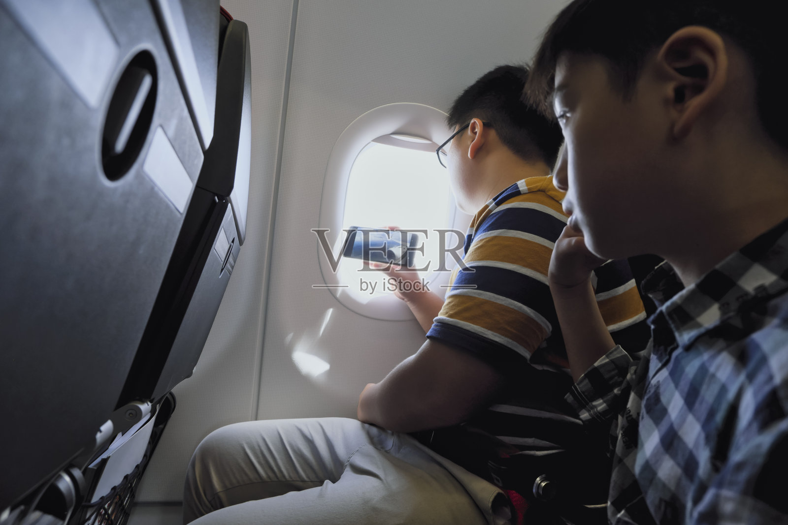 孩子在飞机上使用智能手机照片摄影图片