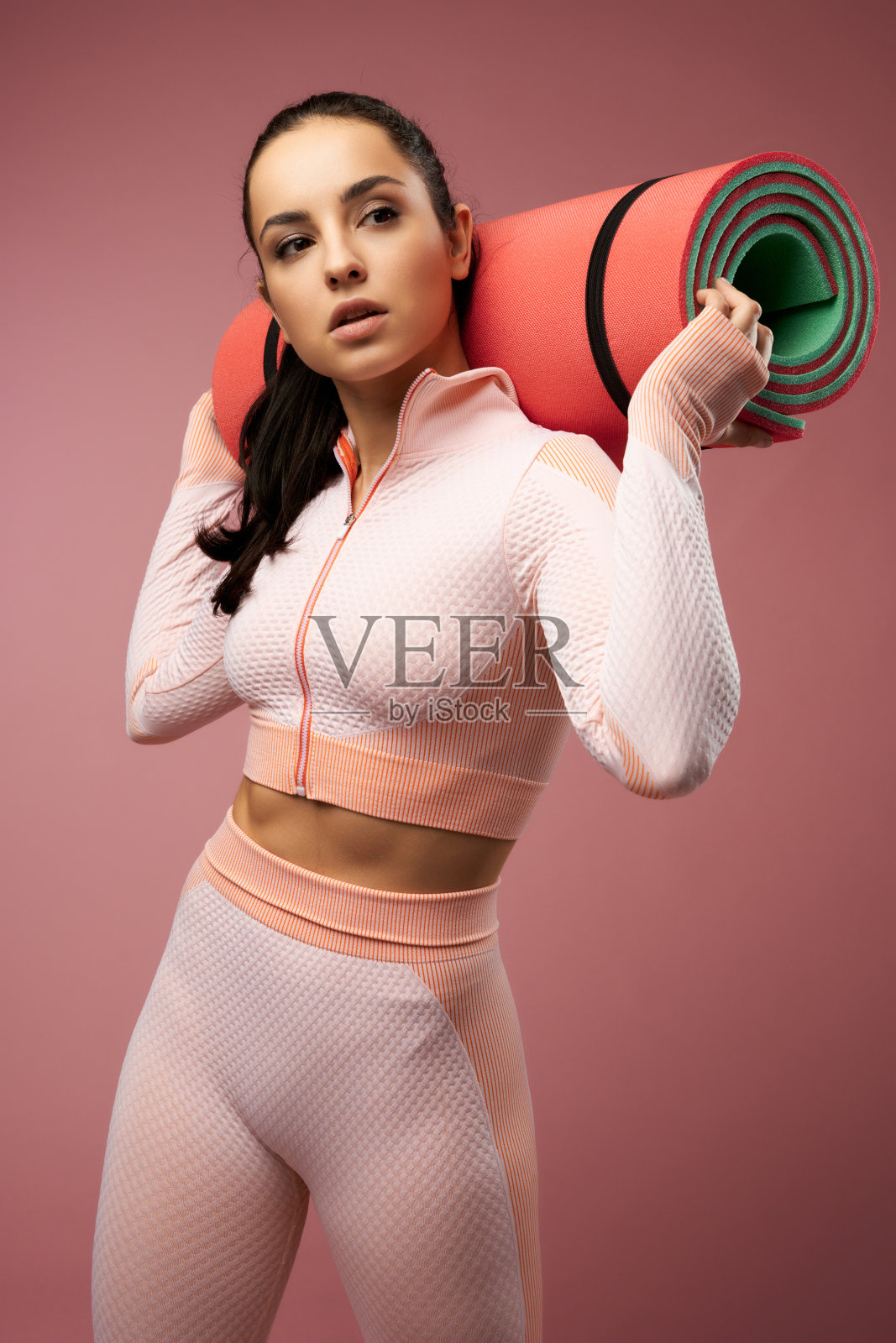 年轻漂亮的女人穿着运动服拿着瑜伽垫照片摄影图片