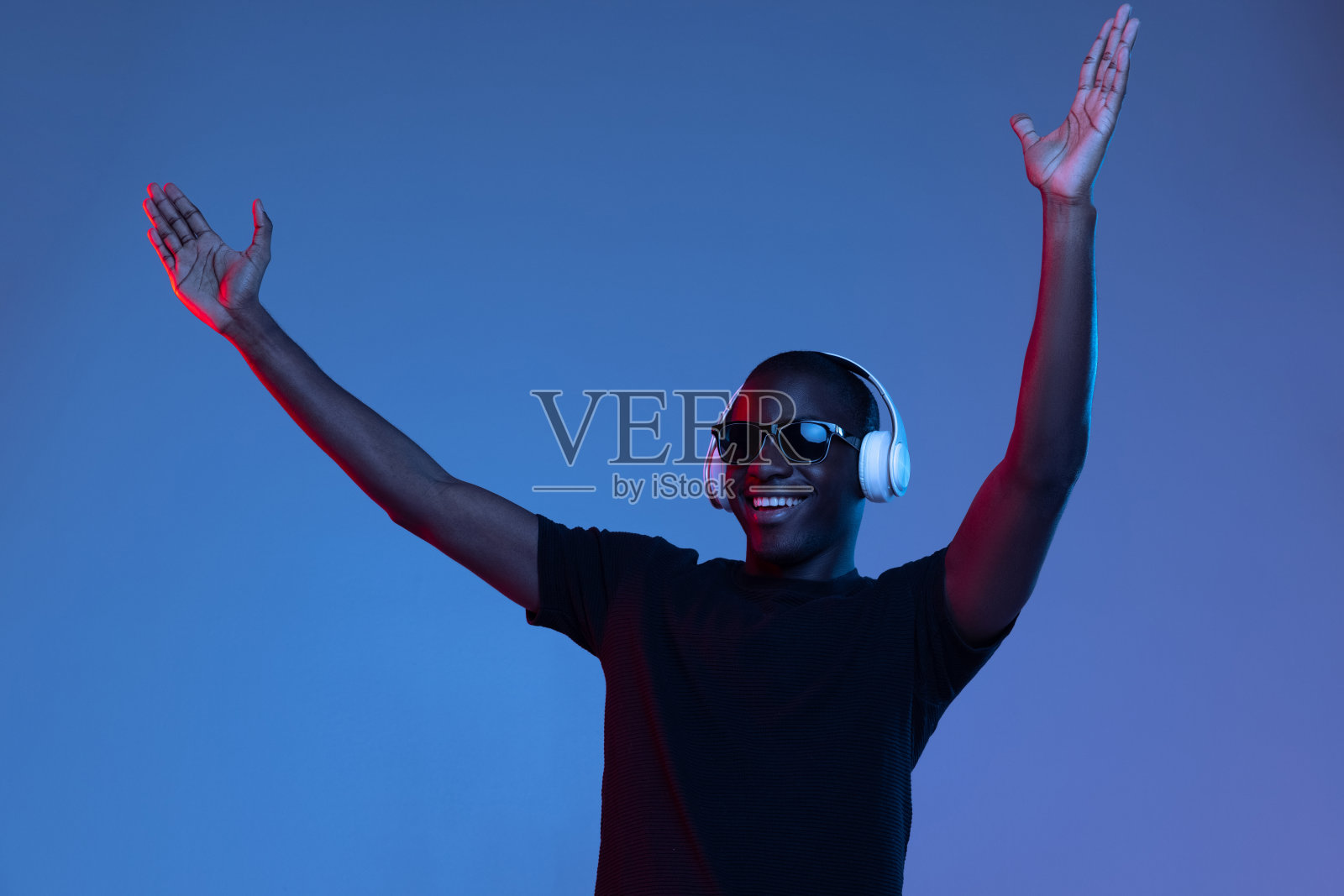 年轻的非洲英俊男子的肖像，摆出孤立的黑色背景在混合霓虹灯。照片摄影图片