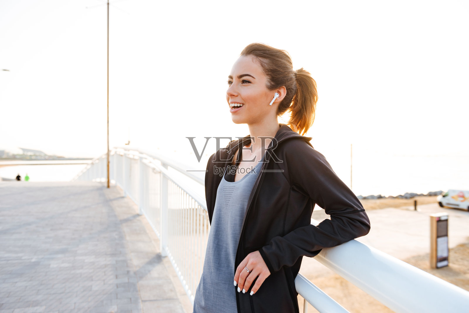 快乐的年轻女运动员用耳机听音乐。照片摄影图片