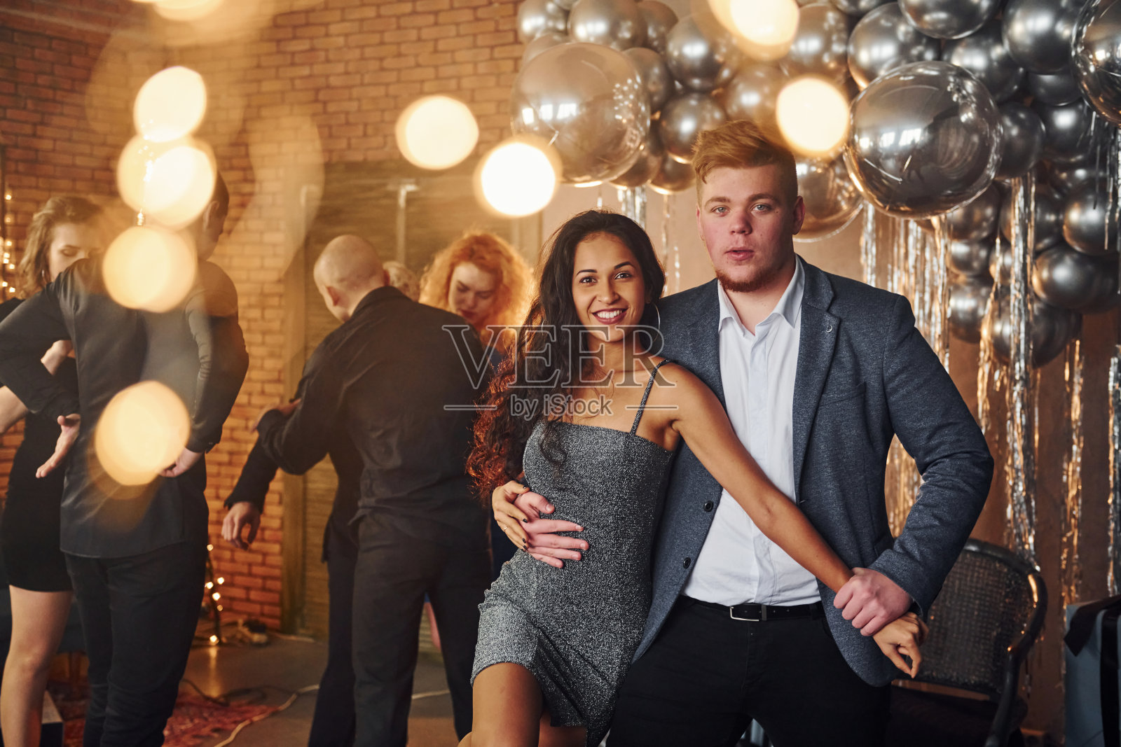 年轻夫妇站在一起对他们的朋友在圣诞装饰房间和庆祝新年照片摄影图片