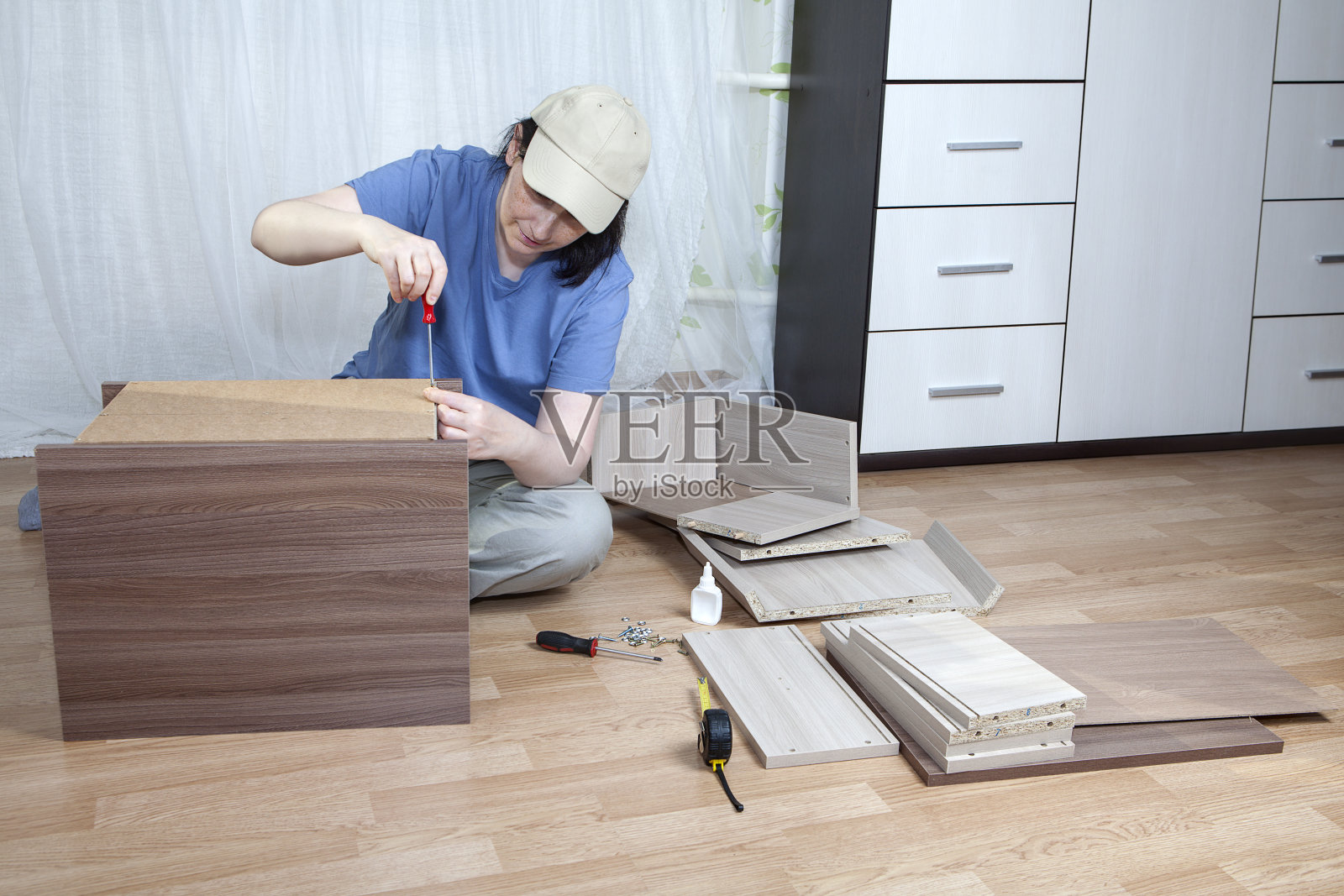 DIY组装平装家具，成熟女人螺丝紧固螺丝。照片摄影图片