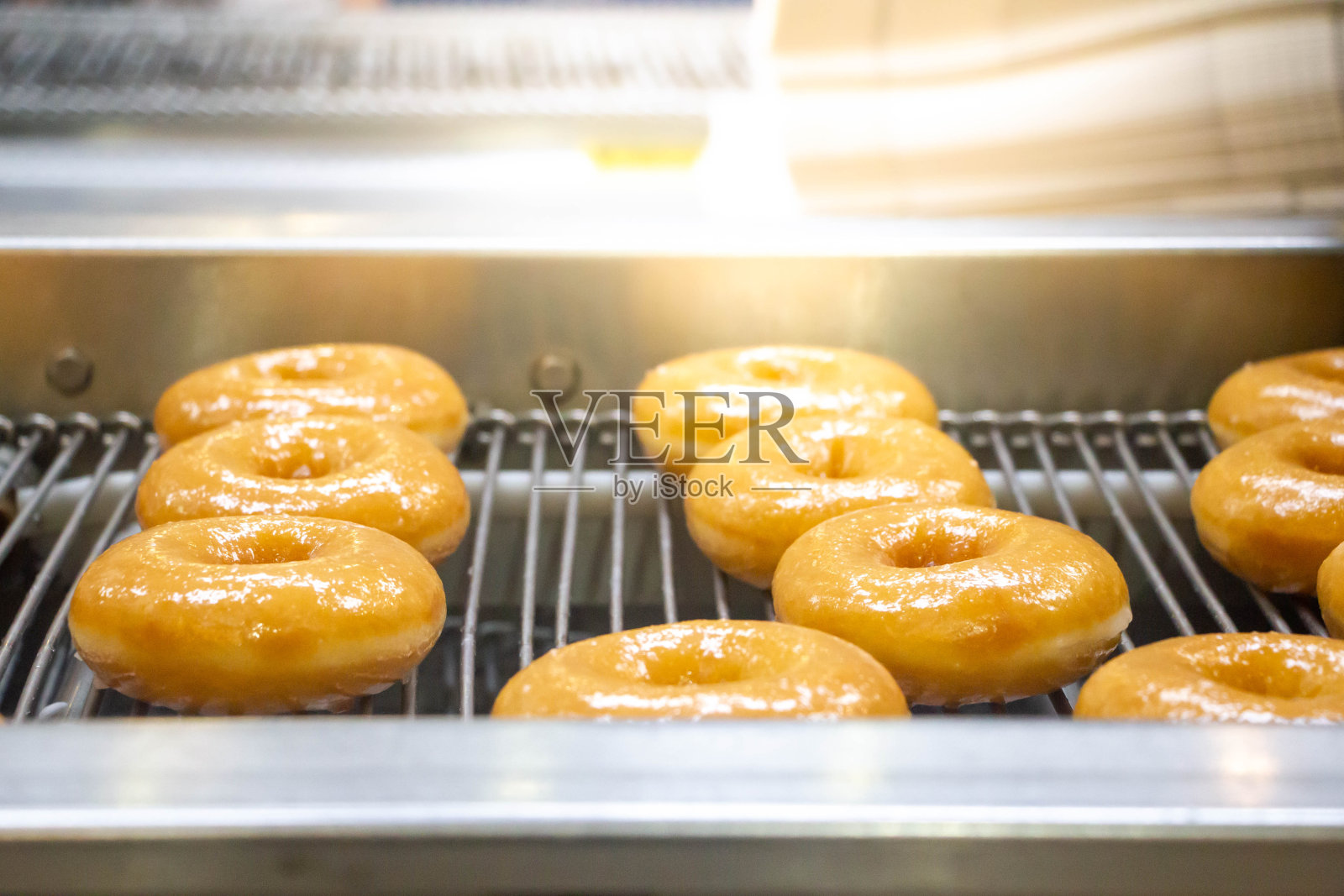 甜甜圈或工厂传送带上的甜甜圈，一种油炸面团糖果或甜点食品照片摄影图片