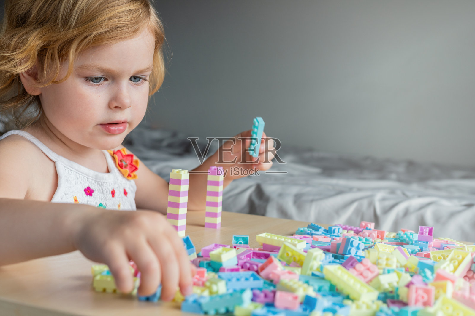 小女孩坐在桌前，玩着五颜六色的积木玩具。照片摄影图片