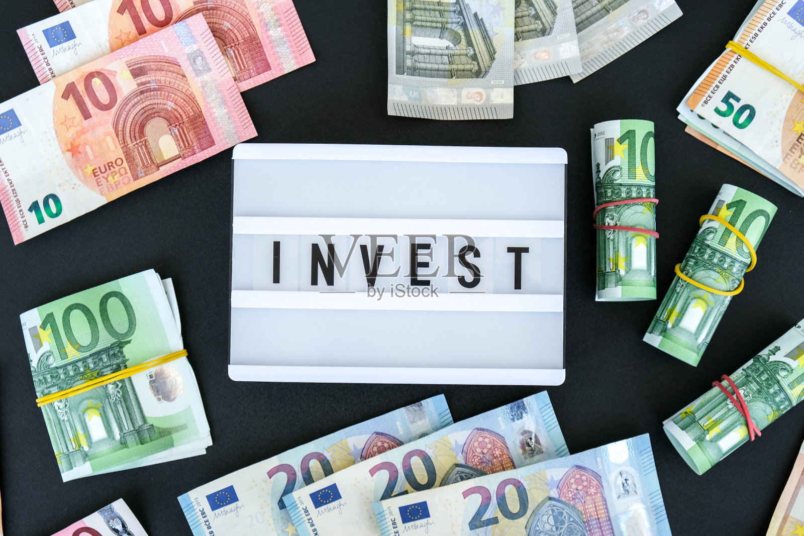 欧元钞票周围黑字“投资”的灯箱牌。金钱，商业，金融，投资，储蓄照片摄影图片