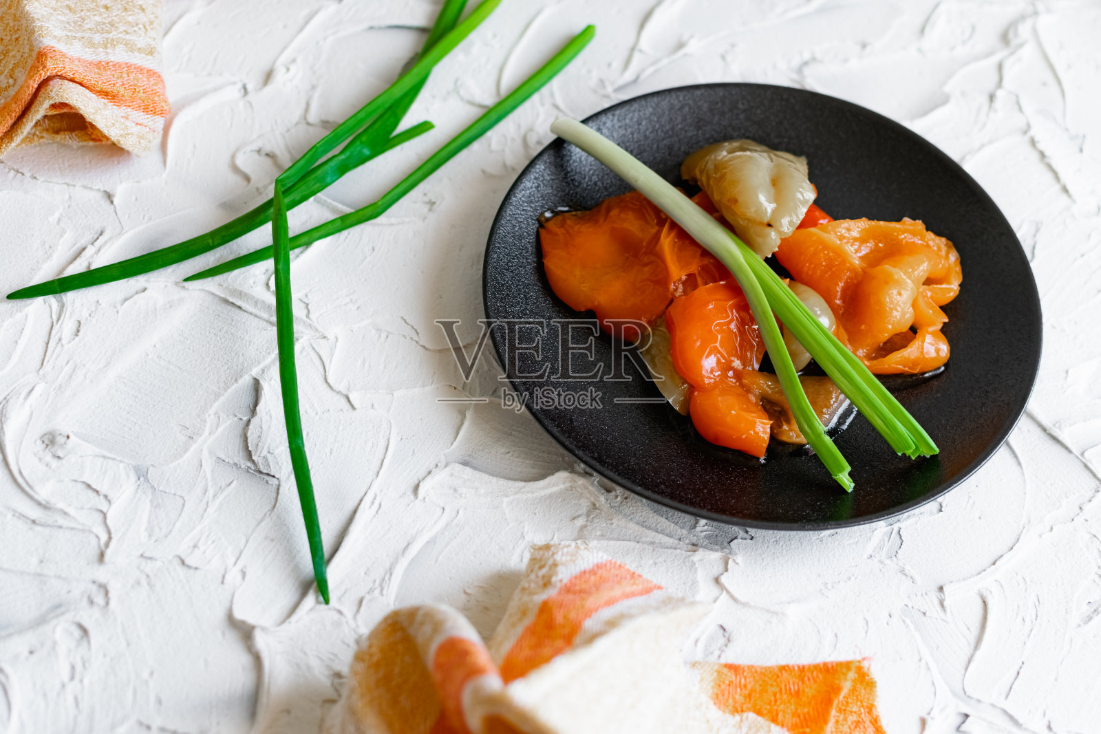 腌好的自制甜椒，配上青葱，放在黑色盘子里。鲜亮多汁冰镇小吃照片摄影图片