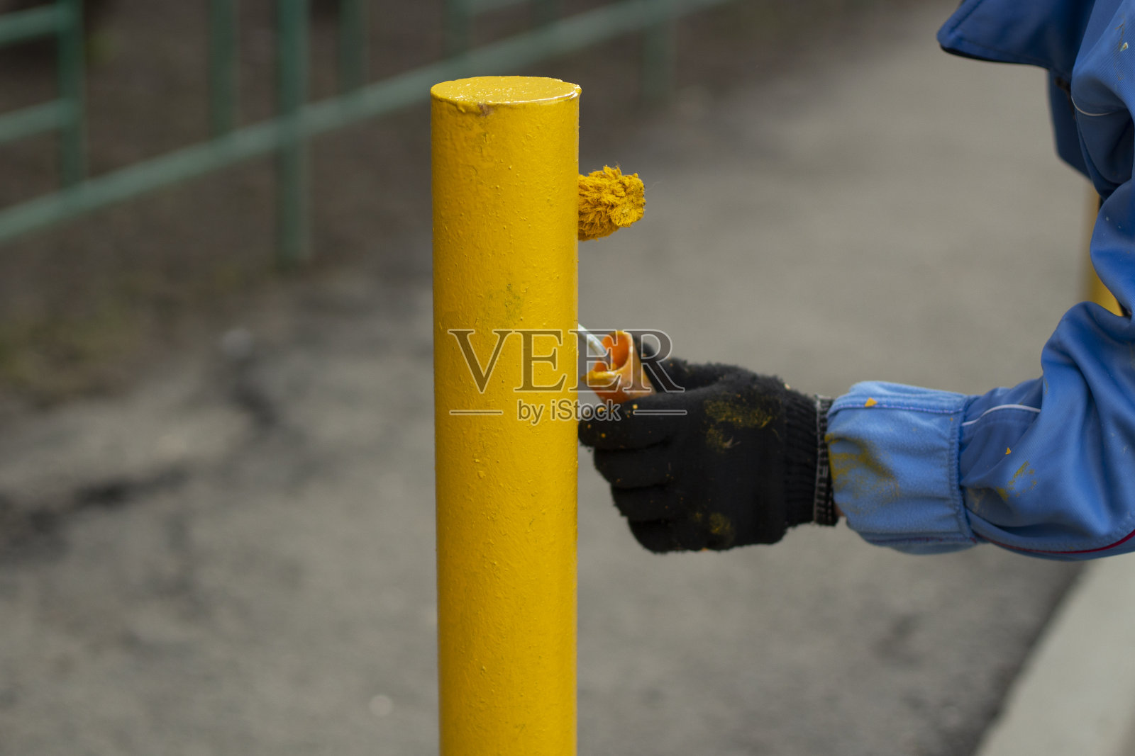 用黄色油漆涂金属柱子。停车带缆桩绘画。照片摄影图片