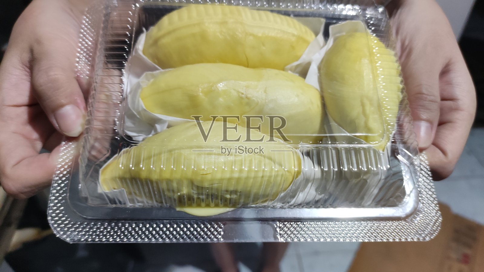 榴莲用纸包在一个透明的塑料盒子里。照片摄影图片