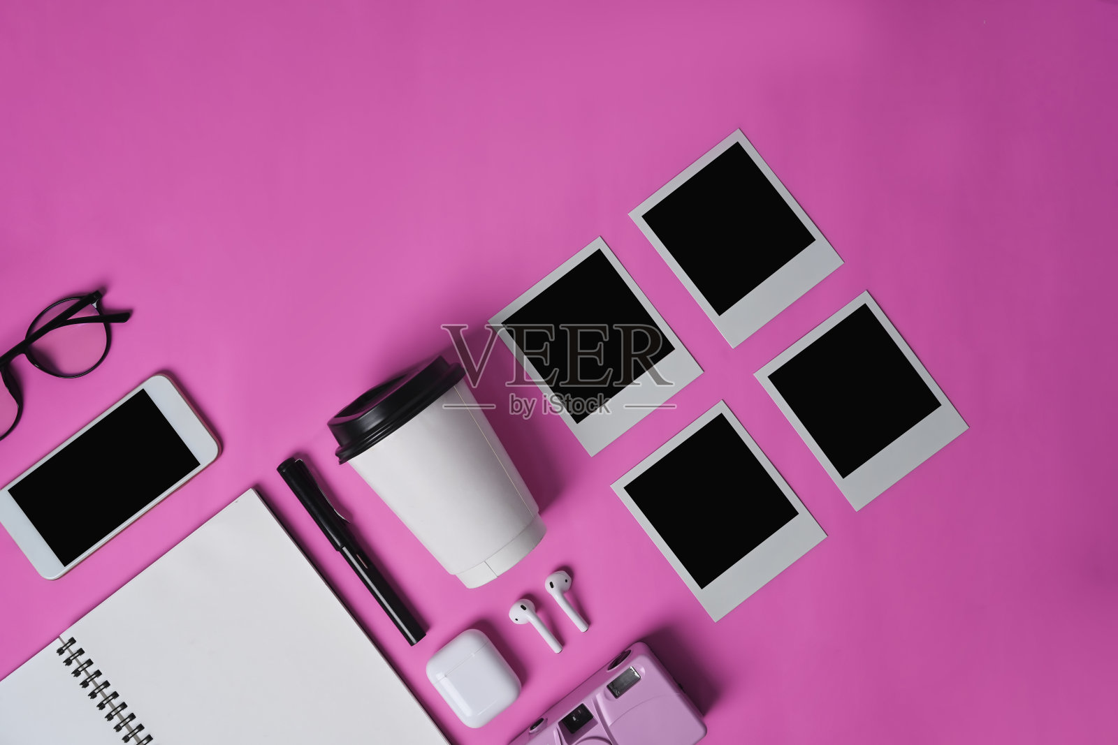 模拟智能手机，耳机，笔记本，杯子和空白相框在粉红色的背景。照片摄影图片