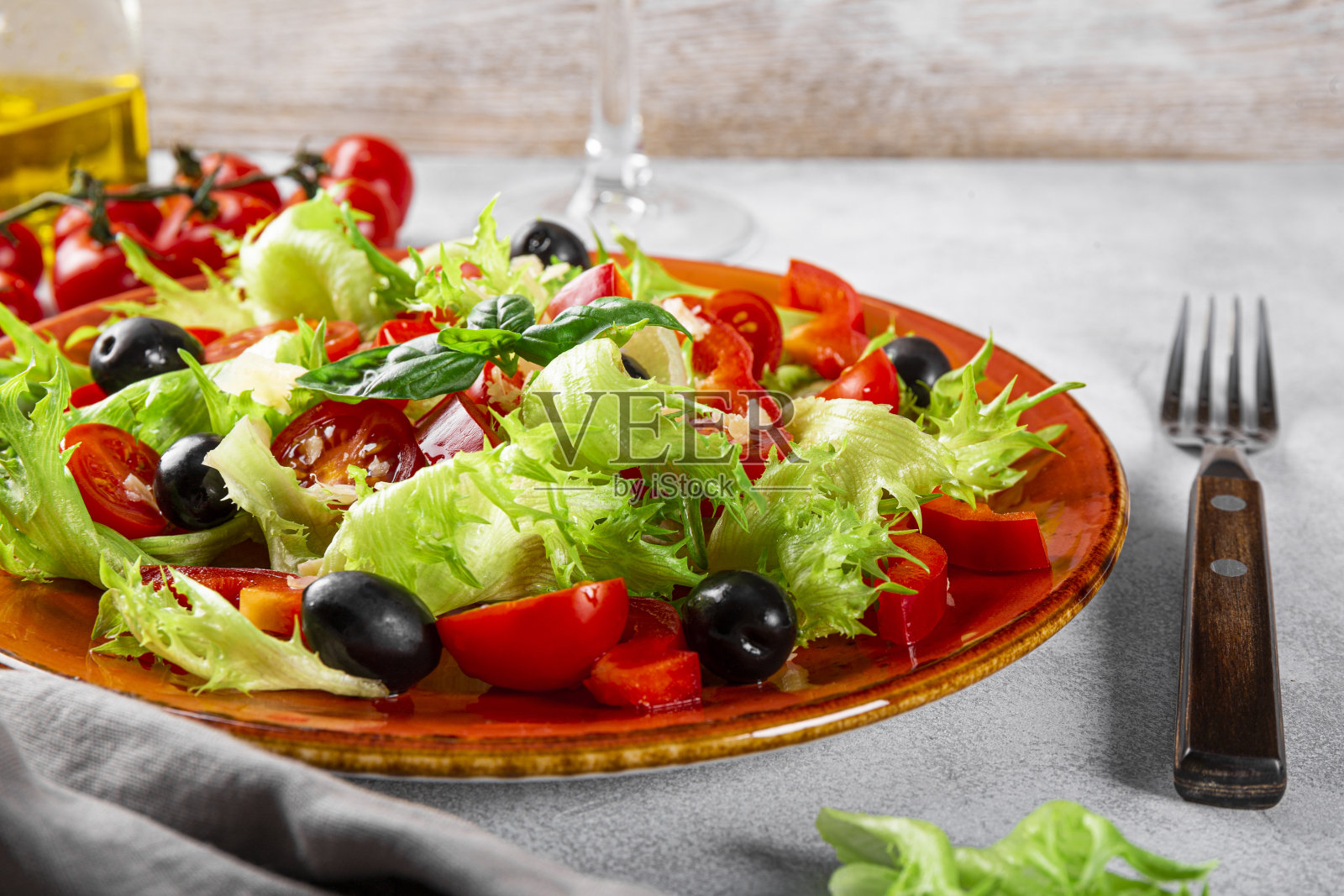 简单的夏季沙拉，生菜，番茄，橄榄和橄榄油在一个红色的盘子上特写照片摄影图片